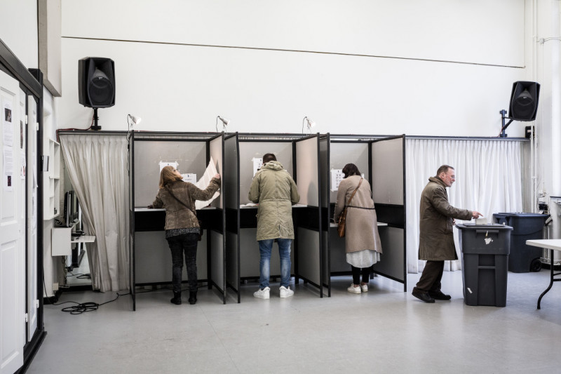 Mensen in een stemhokje tijdens de Nederlandse verkiezingen