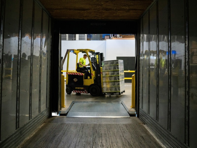 Man rijdt met vorkheftruck, gefotografeerd vanuit lege vrachtwagen